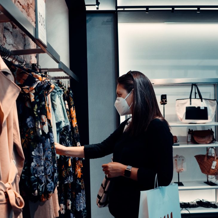mujer con mascarilla de compras en tienda de ropa