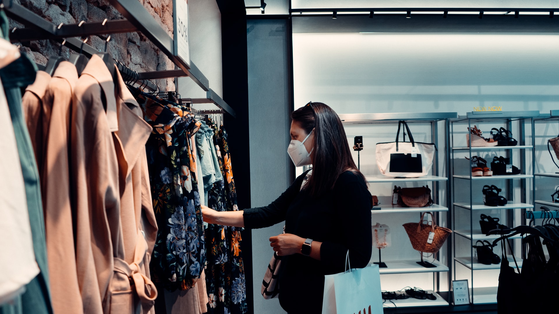 mujer con mascarilla de compras en tienda de ropa