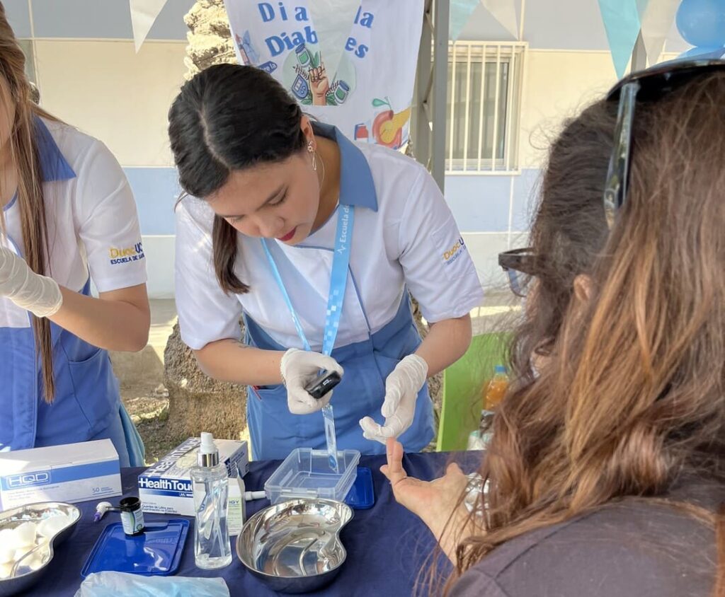 Estudiante midiendo la glicemia de paciente
